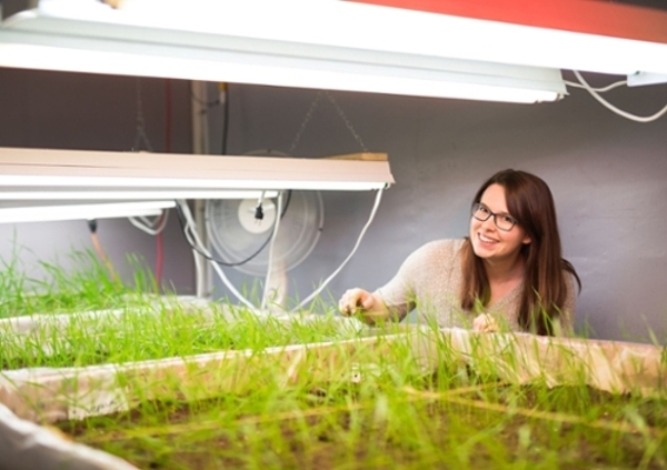 Female student standing next to plants.