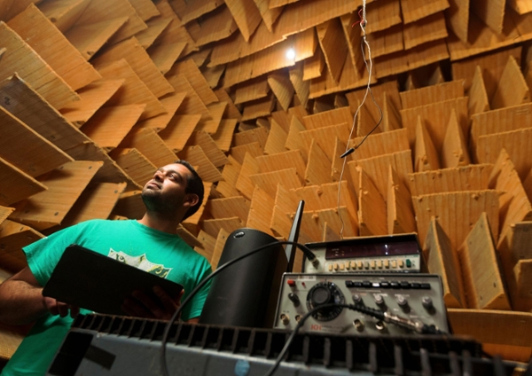 Male student in an anechoic chamber using equipment.