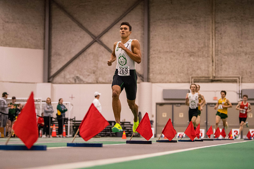 Photo of Dylan Bauman running indoors at a track and field meet