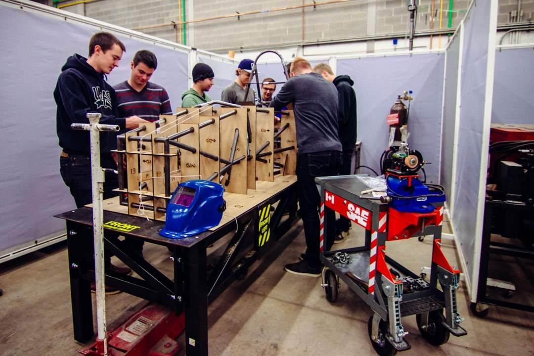 A group of students working on a car chassis.