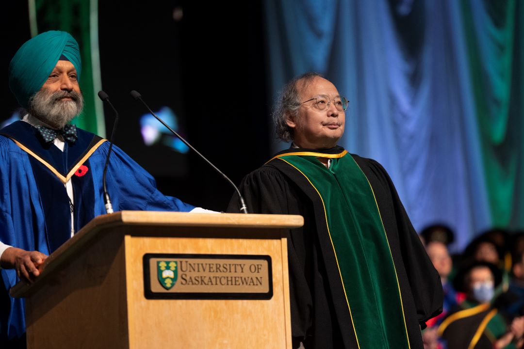 Two men wearing ceremonial gowns standing on a stage.